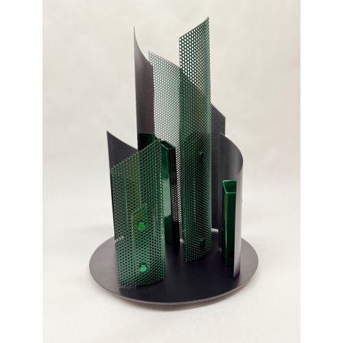 A metal sculpture that sits on a pedestal. The sculpture is green and gray with upward direction panels the tallest being 16 inches and the shortest10 inches. There are 7 panels on at 12 inch diameter metal base.