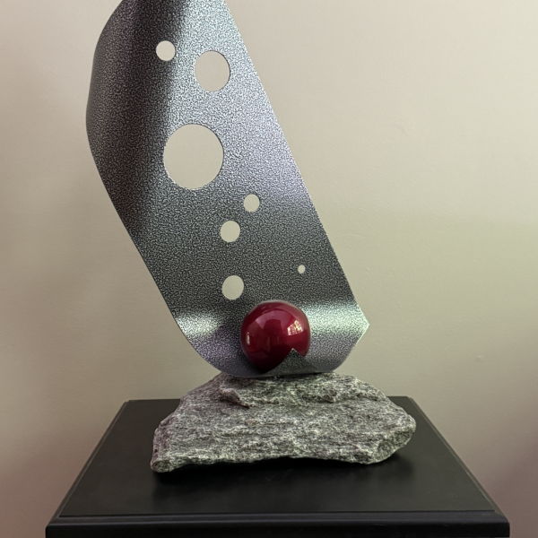 gray textured sheet of steel cradling a bright red sphere; rock base